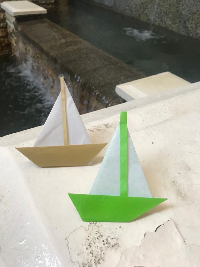 Origami sailboats next to a fountain.